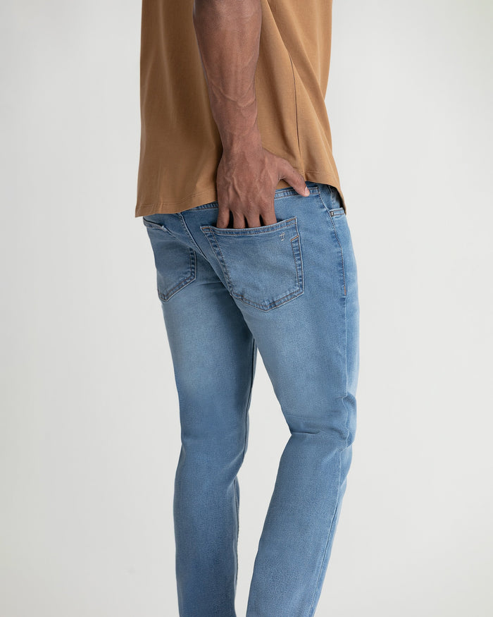 Light indigo skinny fit jeans with five-pocket styling shown on model wearing tan shirt.