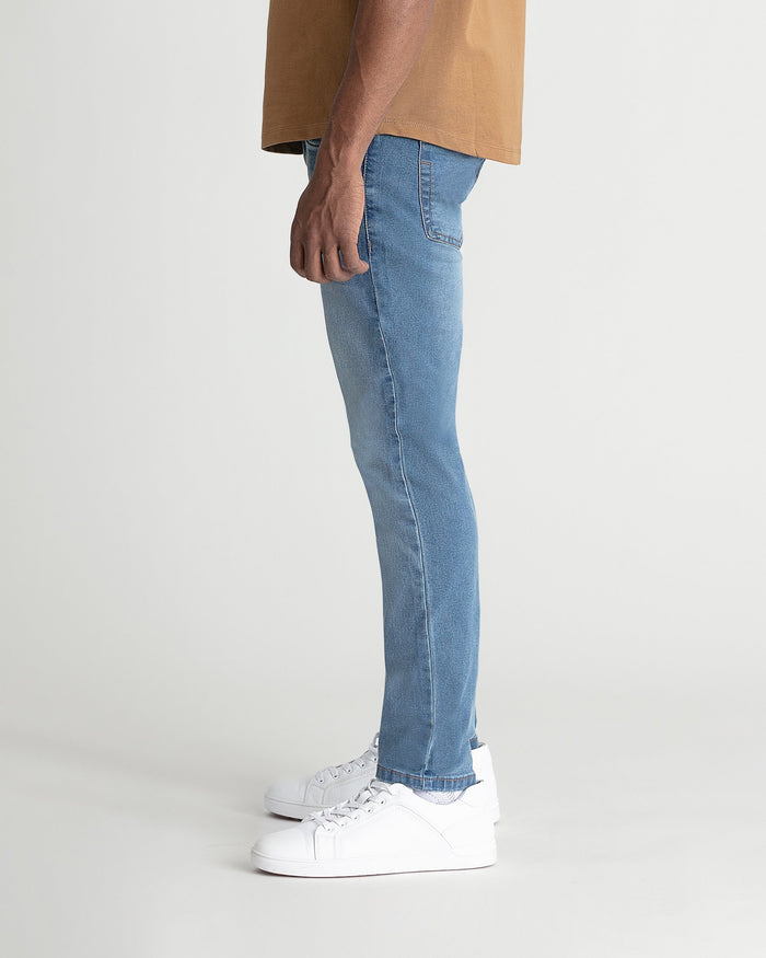Light indigo skinny fit jeans with visible stitching, styled with tan shirt and white sneakers.