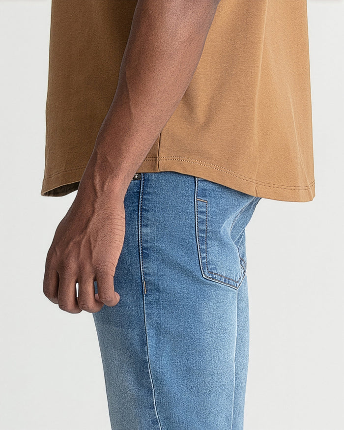 Light indigo skinny fit jeans with visible stitching and pocket detail, worn with tan shirt.