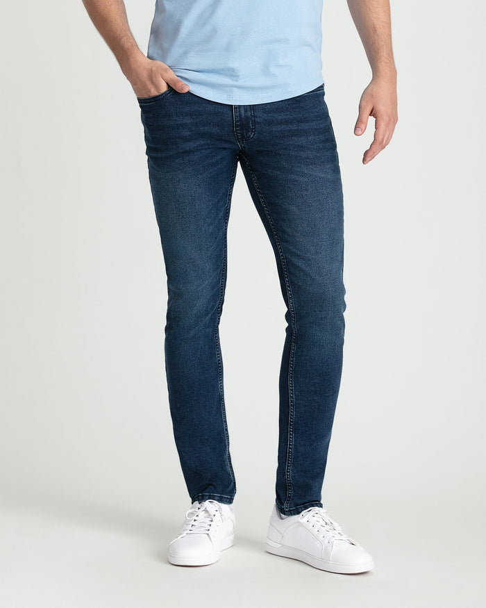 Man wearing light blue t-shirt and dark blue skinny fit jeans with white sneakers.