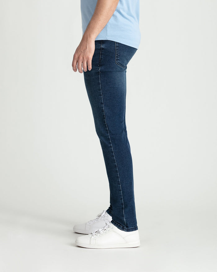 Man wearing dark blue skinny fit jeans with light blue t-shirt and white sneakers.