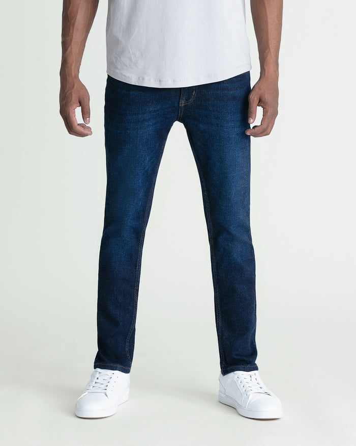 Man wearing dark blue skinny fit jeans with white t-shirt and white sneakers.