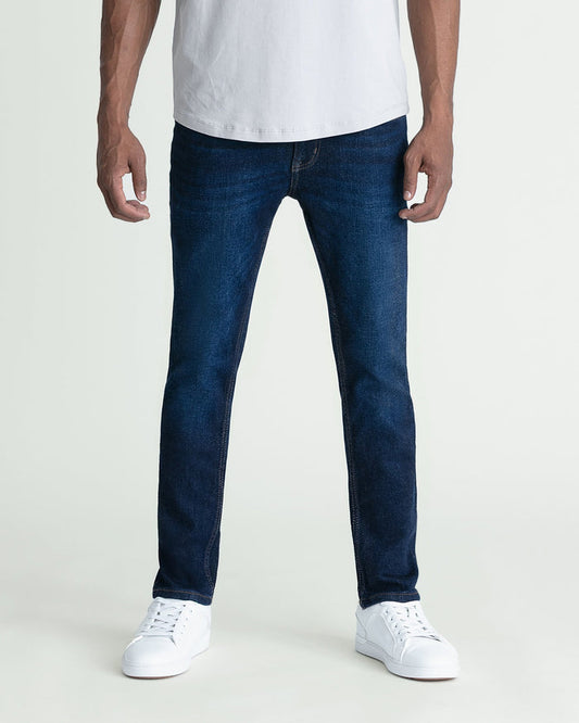 Man wearing dark blue skinny fit jeans with white t-shirt and white sneakers.