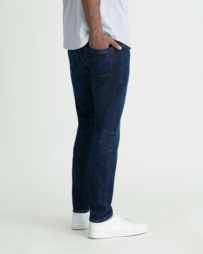 Man wearing dark blue skinny fit jeans with white sneakers and light gray t-shirt.