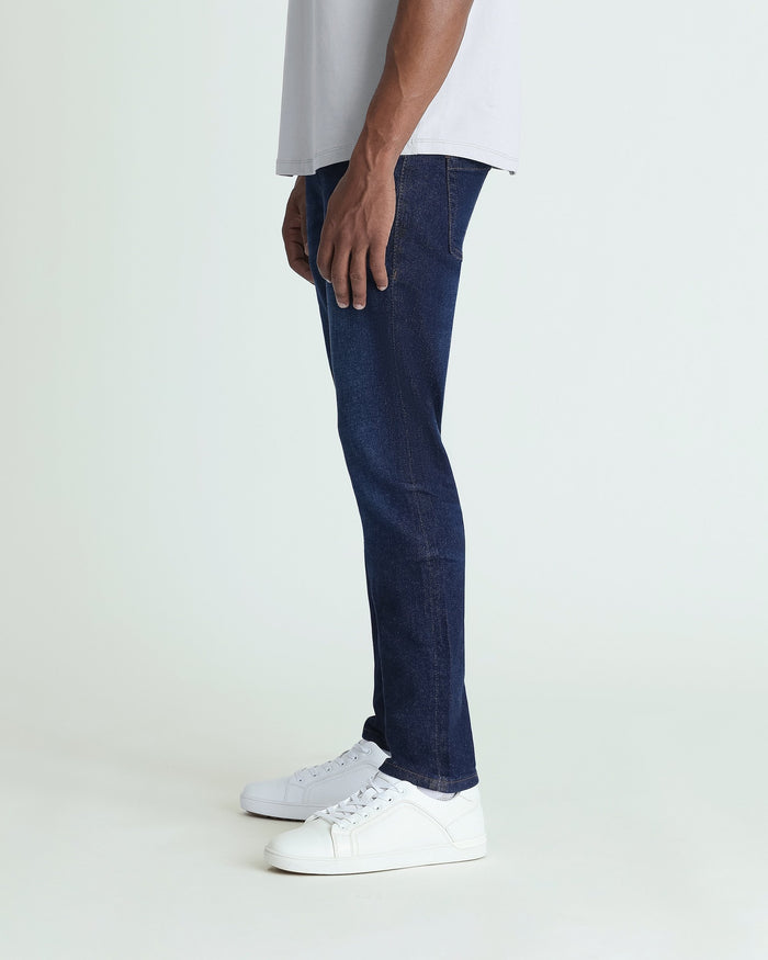 Dark blue skinny fit jeans worn with white sneakers and light gray top, shown from side profile.