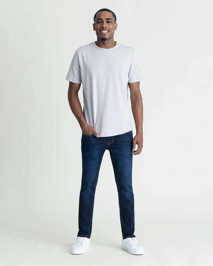 Man wearing light gray t-shirt and dark blue skinny fit jeans with white sneakers.