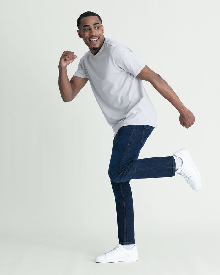 Man wearing white t-shirt and dark blue skinny fit jeans with white sneakers.