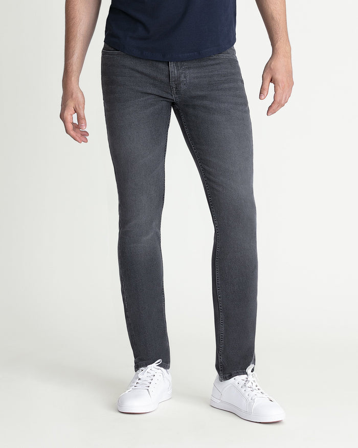 Grey skinny fit jeans on a man wearing a navy shirt and white sneakers.