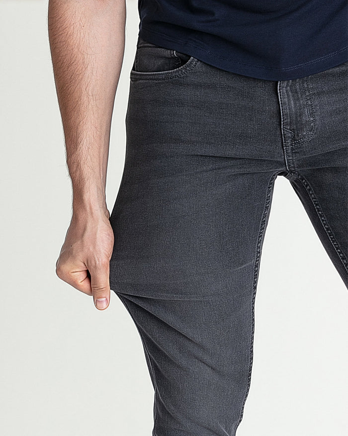 Grey skinny fit jeans on man, close-up of thigh and leg showing tapered silhouette.