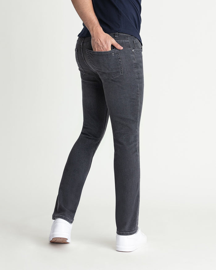 Grey skinny fit jeans with five-pocket styling and visible stitching on a model wearing white sneakers.