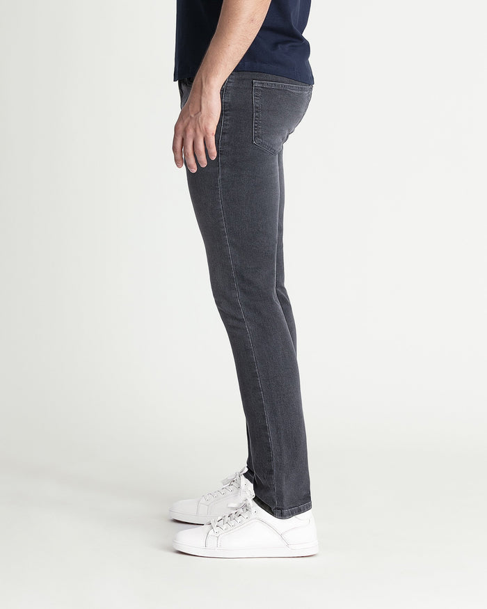 Grey skinny fit jeans worn with white sneakers, shown from the side.