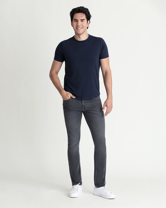 Man wearing navy short-sleeve t-shirt and grey skinny fit jeans with white sneakers.