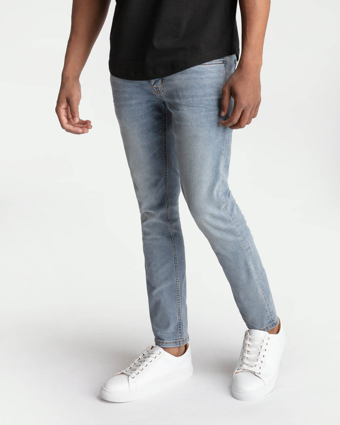Man wearing light blue skinny fit jeans with black t-shirt and white sneakers.