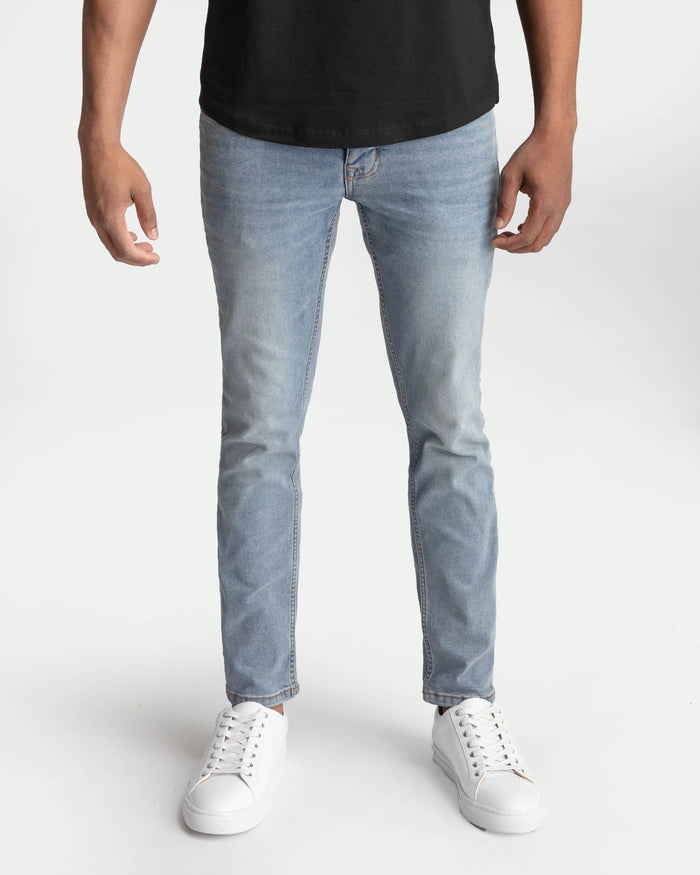 Light blue skinny fit jeans on model wearing black t-shirt and white sneakers.