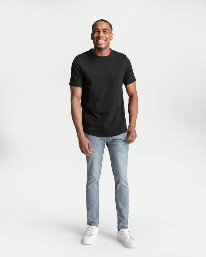 Man wearing black short-sleeve t-shirt and light blue skinny fit jeans with white sneakers.