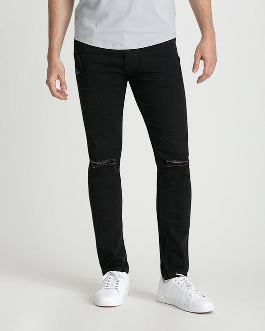 Black skinny fit jeans with ripped knee details worn with white sneakers and gray t-shirt.