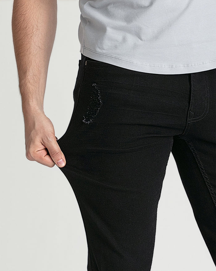 Black skinny fit jeans with ripped detail on thigh, worn with gray t-shirt.