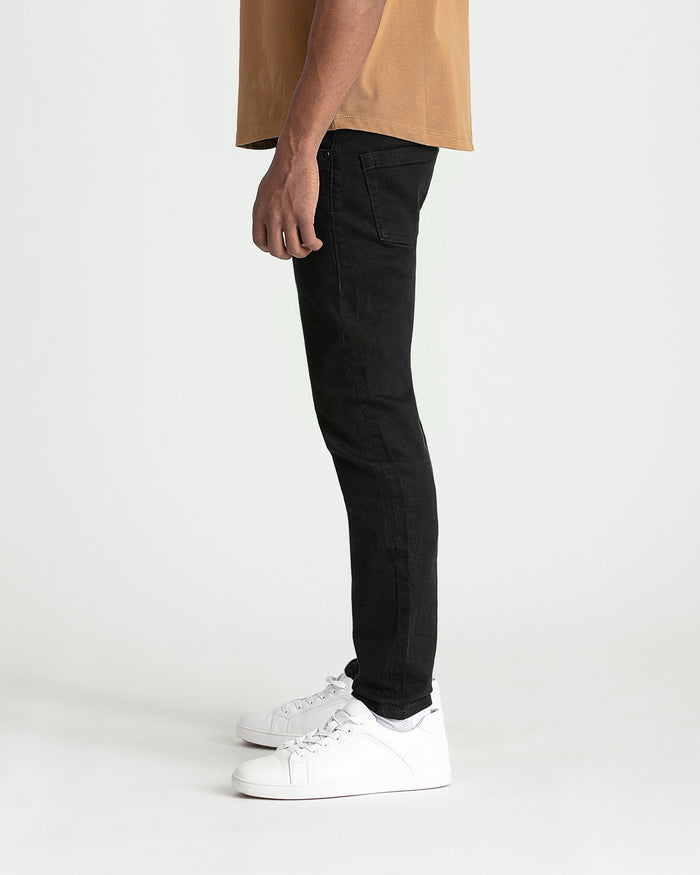 Black skinny fit jeans styled with tan shirt and white sneakers.