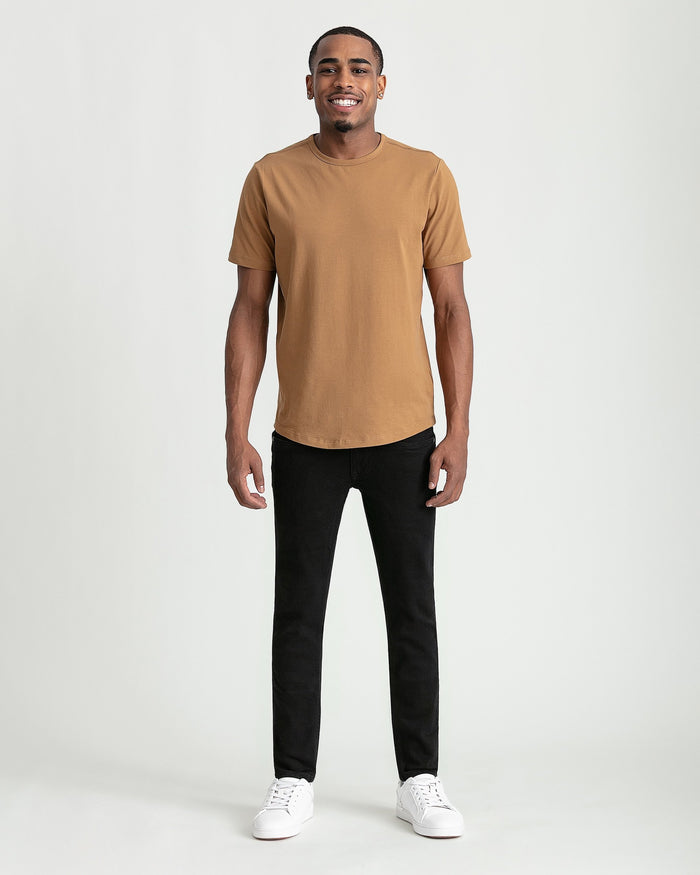 Man wearing tan short-sleeve t-shirt and black skinny fit jeans with white sneakers.