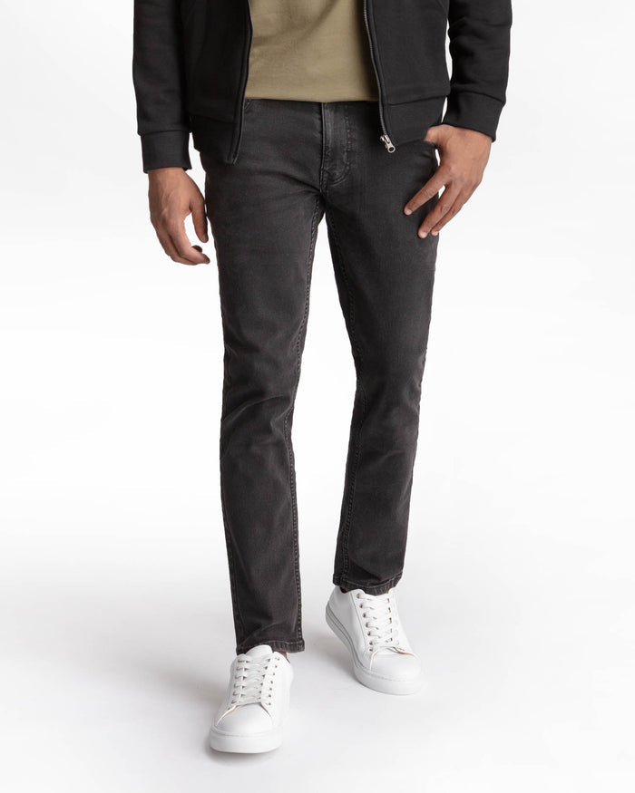 Faded black skinny fit jeans with zip fly, worn with black jacket and white sneakers.