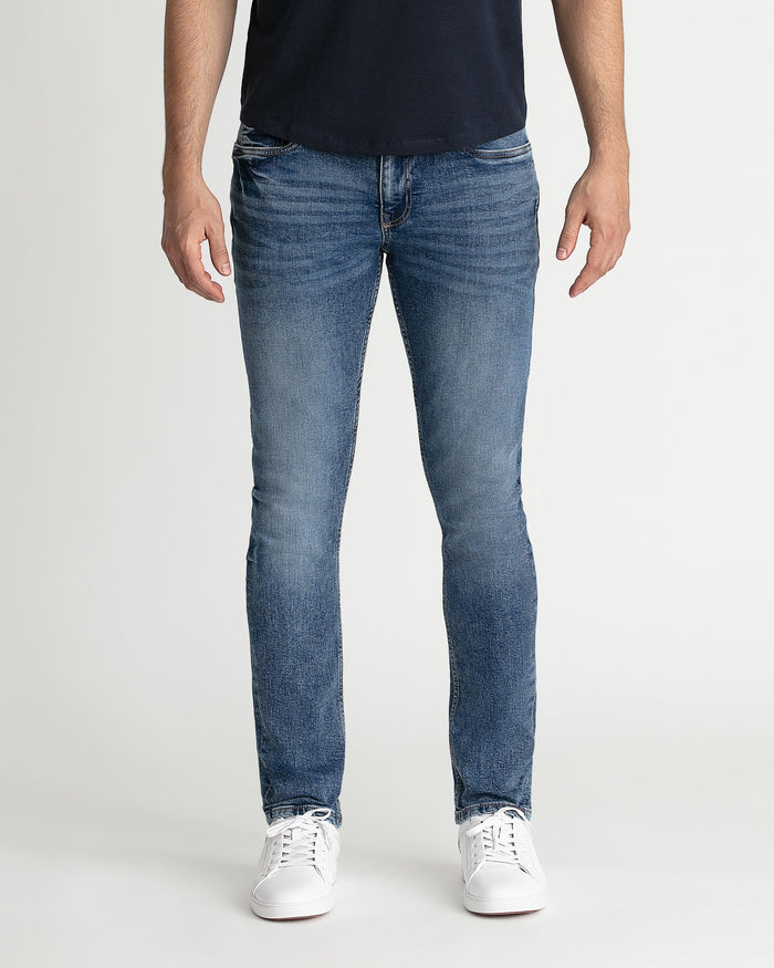 Man wearing medium blue skinny fit jeans with navy t-shirt and white sneakers.
