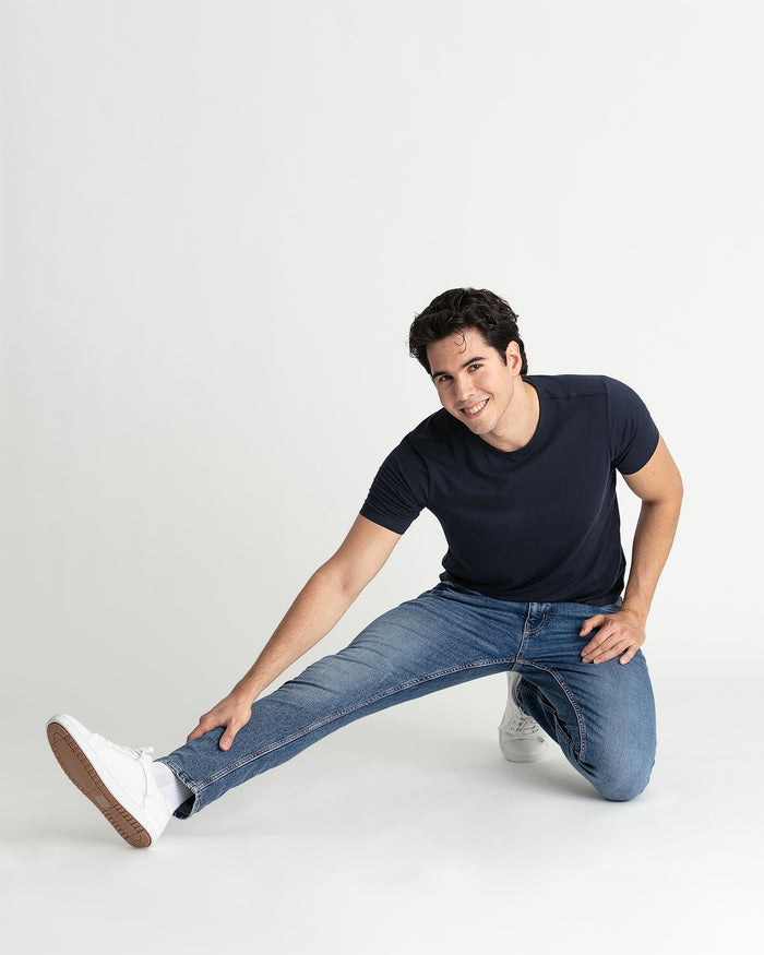 Man wearing medium blue skinny fit jeans with a navy t-shirt and white sneakers.