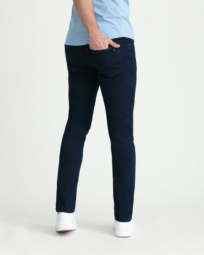 Man wearing light blue shirt and dark blue skinny fit jeans with white sneakers, shown from behind.
