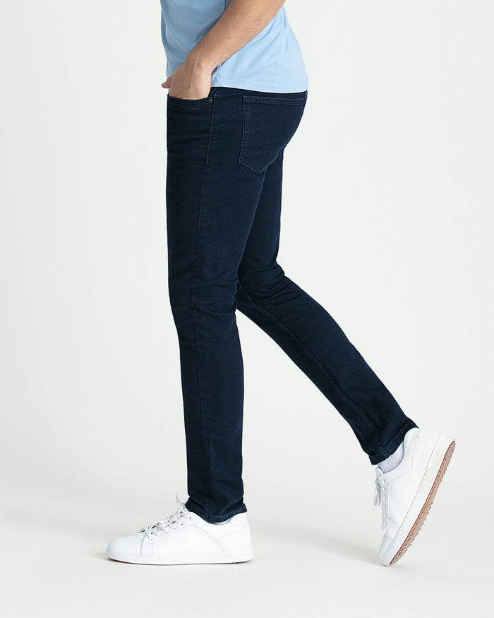 Man wearing dark blue skinny fit jeans with light blue shirt and white sneakers.