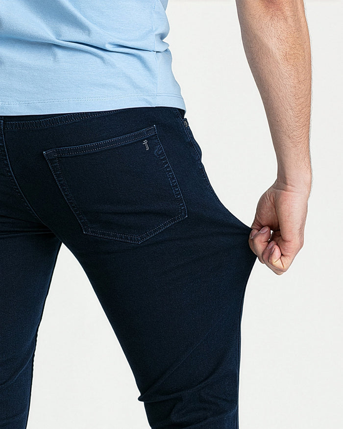 Man wearing light blue t-shirt and deep blue skinny fit jeans with back pocket detail visible.