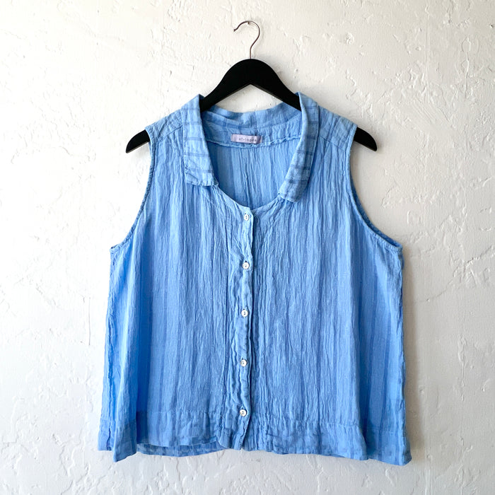 Striped blue sleeveless shirt on a hanger against a white wall
