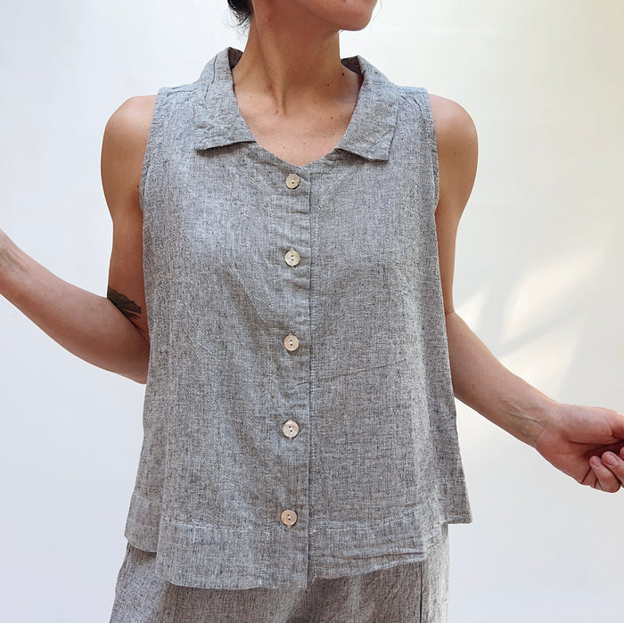 Person wearing a sleeveless gray button-up shirt against a plain background