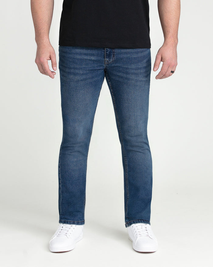 Man wearing medium blue slim fit jeans with black shirt and white sneakers.