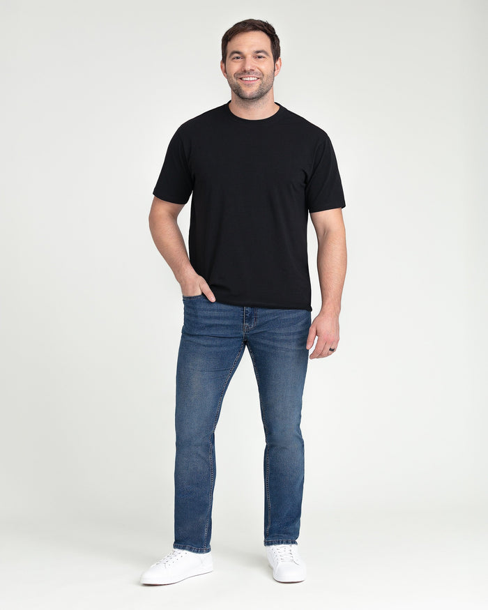 Man wearing black short-sleeve crew neck t-shirt and medium blue slim fit jeans with white sneakers.
