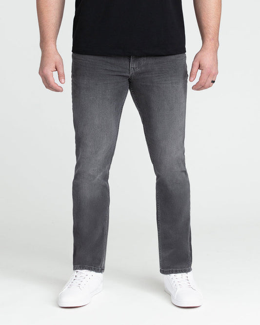 Grey slim fit jeans with straight leg on a model wearing black shirt and white sneakers.