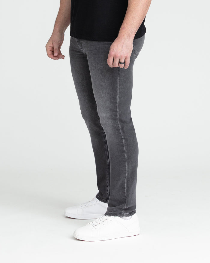Man wearing black t-shirt and grey slim fit jeans with white sneakers.