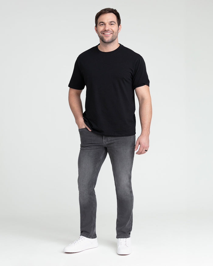 Man wearing black short-sleeve t-shirt and grey slim fit jeans with white sneakers.