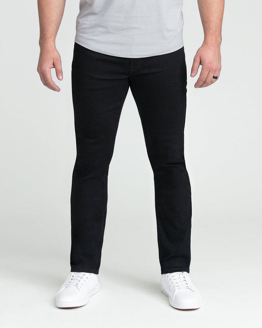 Man wearing black slim fit jeans with white sneakers and light gray t-shirt.