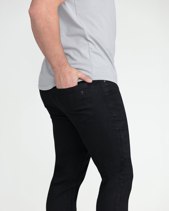 Black slim fit jeans with button fly, styled with light gray t-shirt.