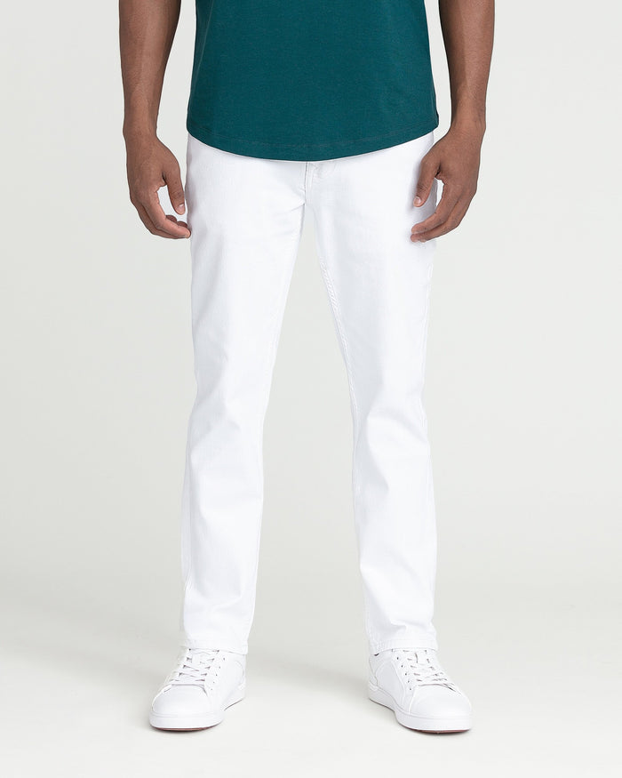 White slim fit jeans with visible stitching, styled with teal shirt and white sneakers.