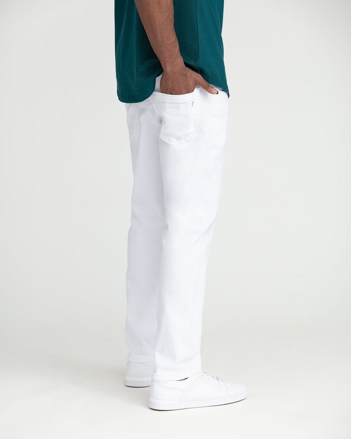 White slim fit jeans on model wearing teal shirt and white sneakers.