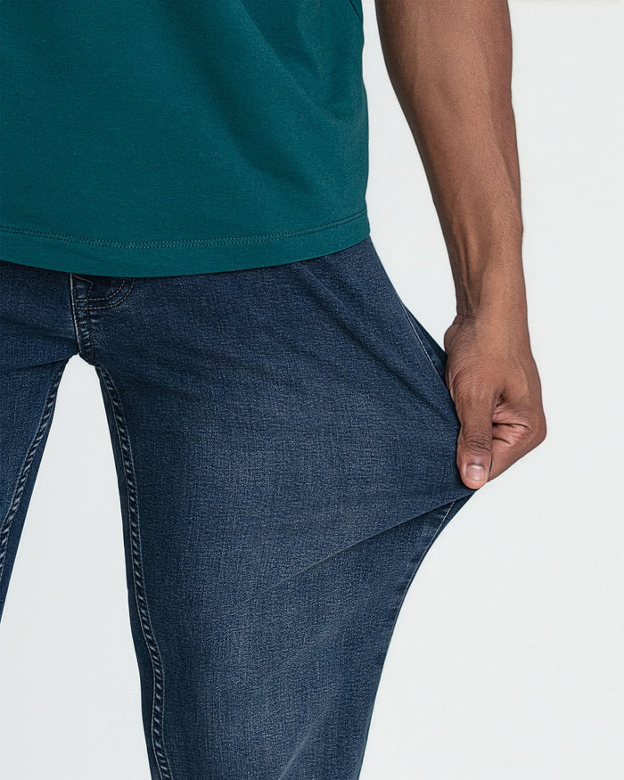 Man wearing teal short-sleeve shirt tucked into dark blue slim fit jeans.