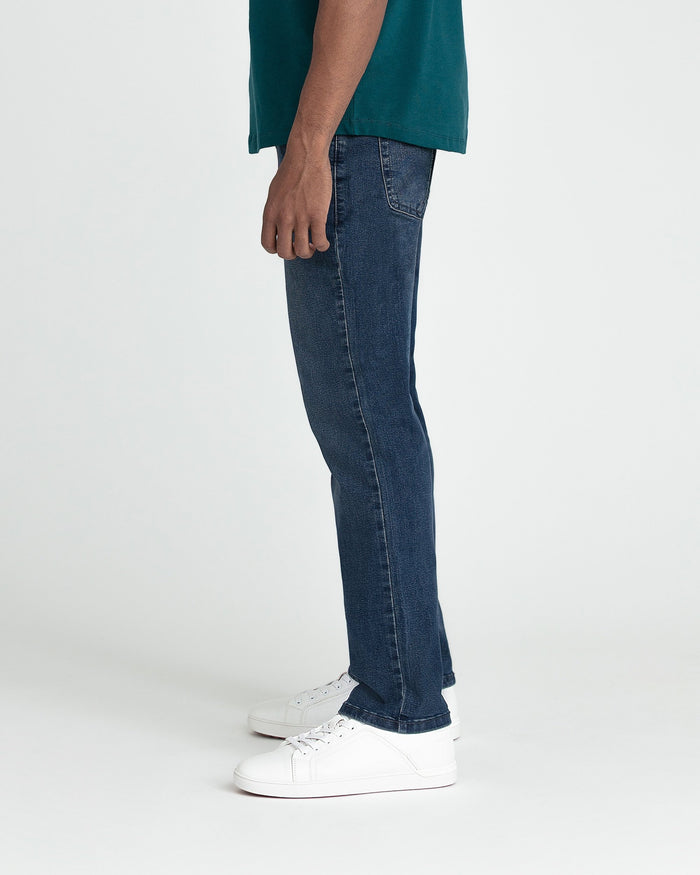 Man wearing midnight blue slim fit jeans with white sneakers and teal shirt.