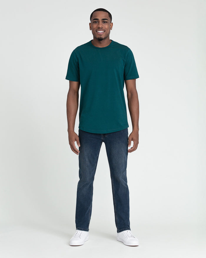 Man wearing dark teal short-sleeve crew neck t-shirt and dark wash slim fit jeans with white sneakers.