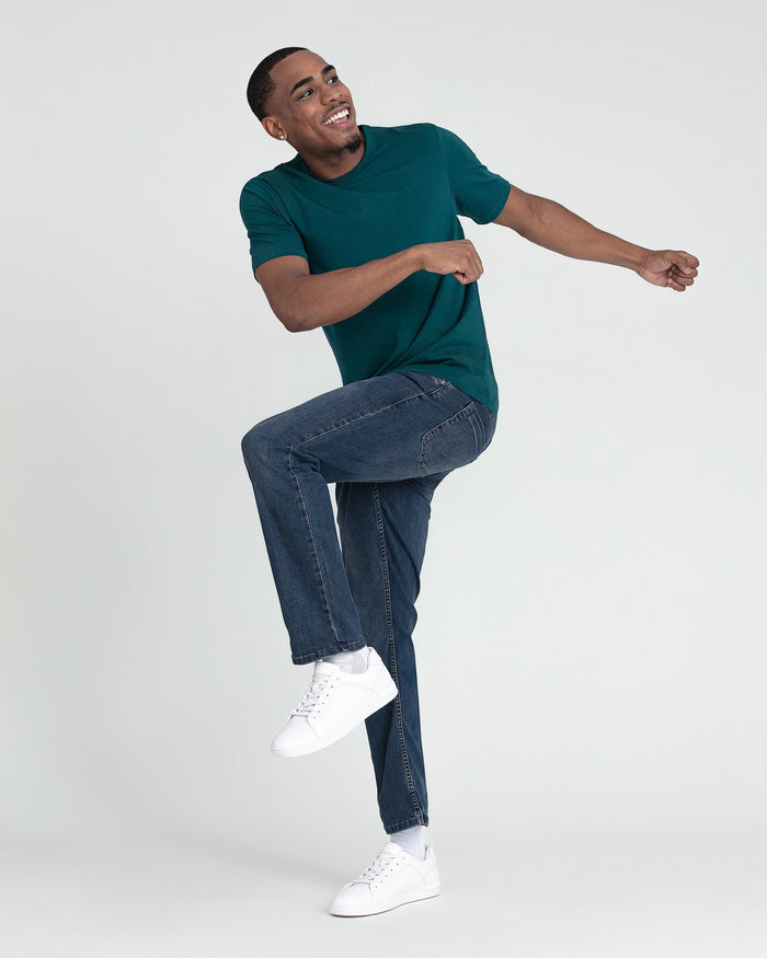Man wearing a midnight blue short-sleeve t-shirt with dark blue slim-fit jeans and white sneakers.