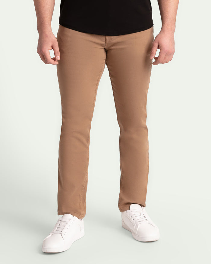 Man wearing dark khaki slim fit pants with black shirt and white sneakers.