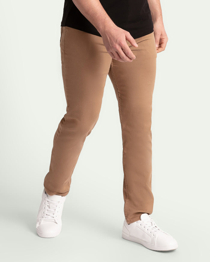 Man wearing dark khaki slim fit pants with white sneakers and black t-shirt.