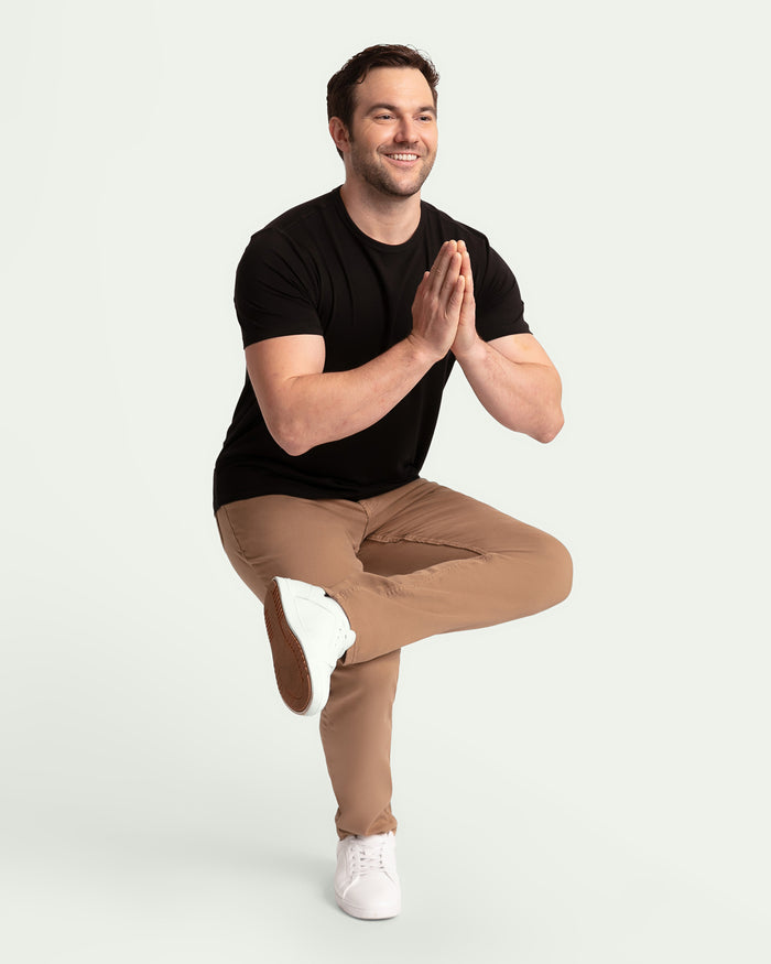 Man wearing black short-sleeve t-shirt and dark khaki slim fit pants with white sneakers.