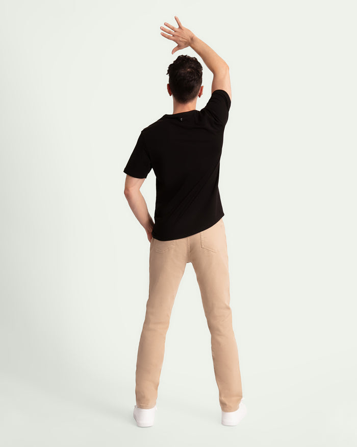 Man wearing black short-sleeve shirt and light khaki slim-fit pants, shown from behind.