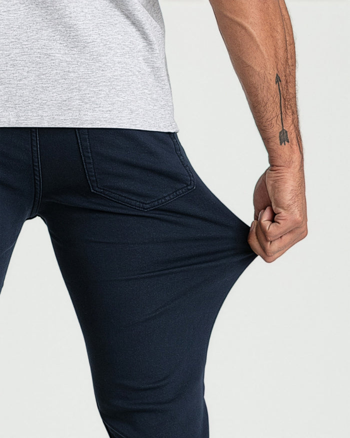 Man wearing light gray t-shirt and navy slim-fit jeans with back pocket detail.