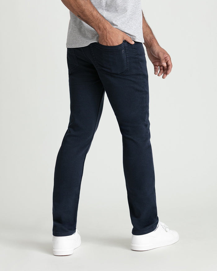 Man wearing slim fit navy jeans with gray t-shirt and white sneakers.
